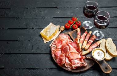 Kırmızı şarap ve breadsticks ile İspanyolca jambon. Rustik siyah arka plan üzerine.