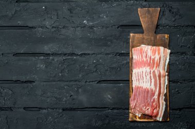 Bir kesme tahtası üzerinde ham pastırma. Rustik siyah arka plan üzerine.