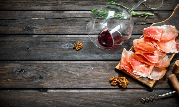 stock image Spanish ham with red wine and nuts. On a wooden background.