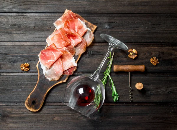 stock image Spanish ham with red wine and nuts. On a wooden background.