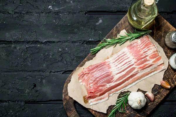 stock image Raw bacon with rosemary and spices. On black rustic background.