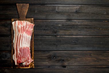 Eski panosunda çiğ domuz pastırması. Ahşap bir arka plan üzerinde.