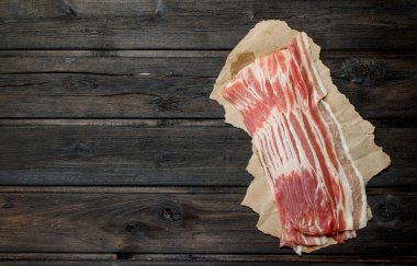Kağıt üzerinde ham pastırma. Ahşap bir arka plan üzerinde.