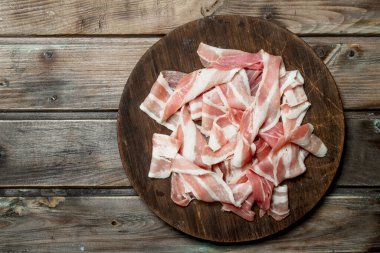 Bir kesme tahtası üzerinde ham pastırma. Ahşap bir arka plan üzerinde.