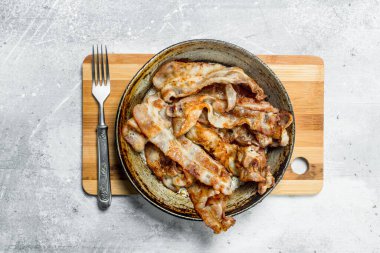 Bir tavada kızarmış domuz pastırması. Rustik bir arka plan üzerinde.