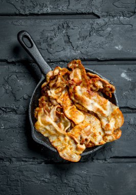 Bir tavada kızarmış domuz pastırması. Rustik siyah arka plan üzerine.