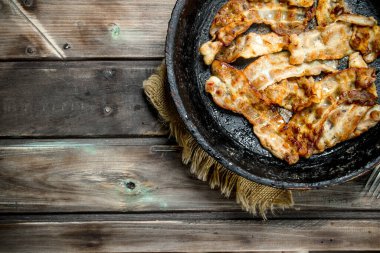 Bir tavada kızarmış domuz pastırması. Ahşap bir arka plan üzerinde.