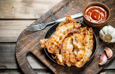 Domates soslu kızarmış domuz pastırması. Ahşap bir arka plan üzerinde.