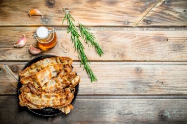 Zeytin yağı ve biberiye ile kızarmış domuz pastırması. Ahşap bir arka plan üzerinde.