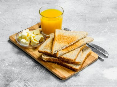 Kahvaltı. Bir bardak portakal suyu ve tereyağı ile ekmek. Rustik bir arka plan üzerinde.