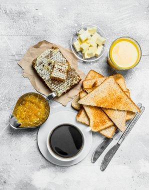 Kahvaltı. Tost ekmeği tereyağı, bal ve portakal reçeli ile. Rustik bir arka plan üzerinde.