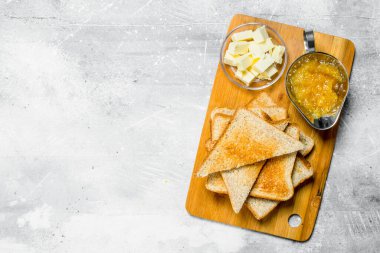 Kahvaltı. Tost ekmeği tereyağı ve reçel ahşap oyun tahtası ile. Rustik bir arka plan üzerinde.