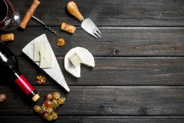 Brie peyniri ile kırmızı şarap, fındık ve üzüm. Ahşap bir arka plan üzerinde.