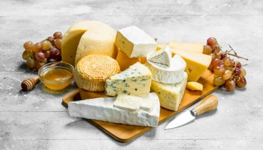 Peynirli olsun bal ve üzüm çeşitleri. Rustik bir arka plan üzerinde.