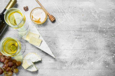 Brie peyniri bal, üzüm ve beyaz şarap ile. Rustik bir arka plan üzerinde.