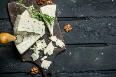 Mavi peynir ile fındık ve biberiye dalları. Siyah bir rustik arka planda.