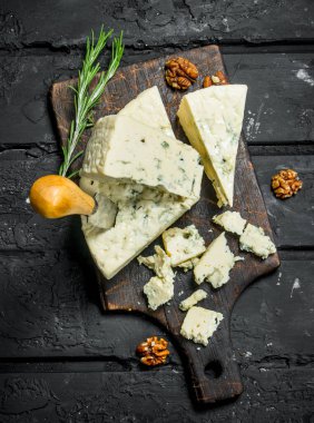 Mavi peynir ile fındık ve biberiye dalları. Siyah bir rustik arka planda.