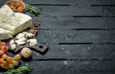 Mavi peynir ceviz ve üzüm. Siyah bir rustik arka planda.