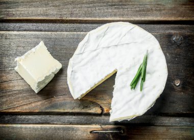 Brie peyniri ince dal biberiye ile. Ahşap bir arka plan üzerinde.