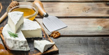 Brie peyniri ile bal ve üzüm. Ahşap bir arka plan üzerinde.