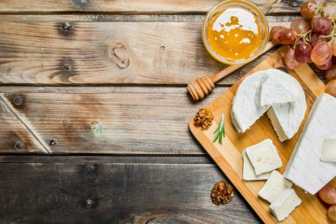 Brie peyniri üzüm, fındık ve bal yönetim kurulu ile. Ahşap bir arka plan üzerinde.