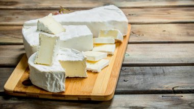 Brie peyniri kesme tahtası üzerinde. Ahşap bir arka plan üzerinde.