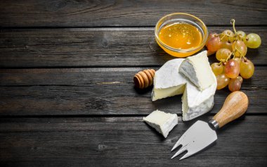 Brie peyniri ile bal ve üzüm. Ahşap bir arka plan üzerinde.