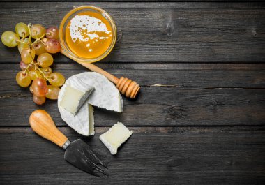 Brie peyniri ile bal ve üzüm. Ahşap bir arka plan üzerinde.