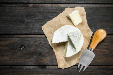 Brie peyniri eski kağıt üzerinde. Ahşap bir arka plan üzerinde.