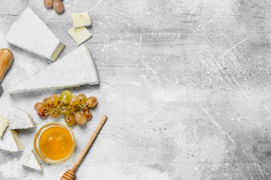 Brie peyniri ile bal ve üzüm. Rustik bir arka plan üzerinde.