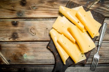İnce dilim peynir kesme tahtası üzerinde. Ahşap bir arka plan üzerinde.