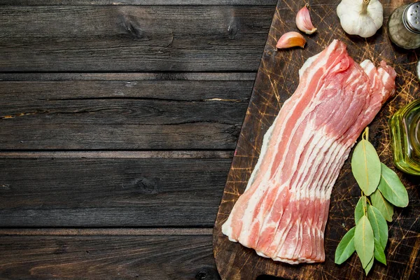 stock image Raw bacon with garlic and aromatic spices. On a wooden background.