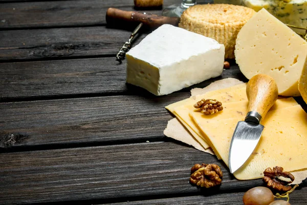 不同奶酪与葡萄和核桃的组合 在木制背景 — 图库照片