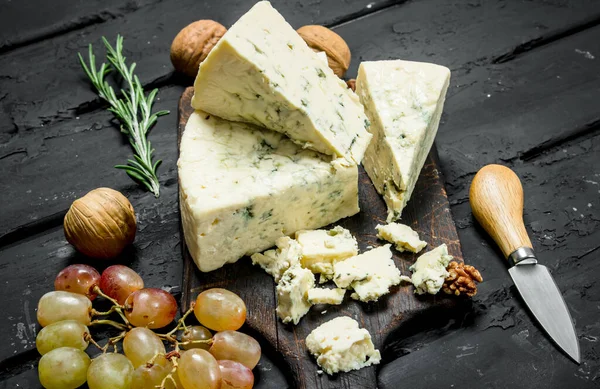 stock image Blue cheese with grapes and rosemary. On a black rustic background.