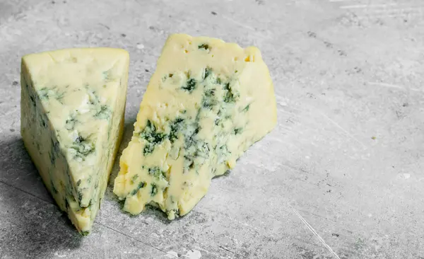 stock image Pieces of blue cheese. On a rustic background.