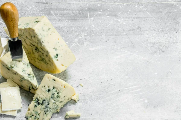 stock image Blue and brie cheese with knives. On a rustic background.