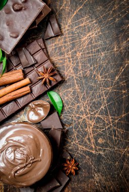 Tarçın ve çikolata dilimleri ile çikolata ezmesi. Ahşap bir arka plan üzerinde