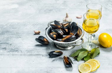 Şarap ve limon dilimleri ile taze deniz ürünleri istiridye. Rustik bir arka plan üzerinde.