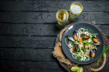 Akdeniz yemekleri. Deniz mahsulleri spagetti istiridye ve beyaz şarap. Siyah bir rustik arka planda.