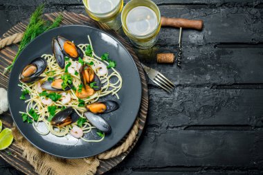 Akdeniz yemekleri. Deniz mahsulleri spagetti istiridye ve beyaz şarap. Siyah bir rustik arka planda.