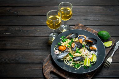 Akdeniz yemekleri. Deniz mahsulleri spagetti istiridye ve beyaz şarap. Ahşap bir arka plan üzerinde.