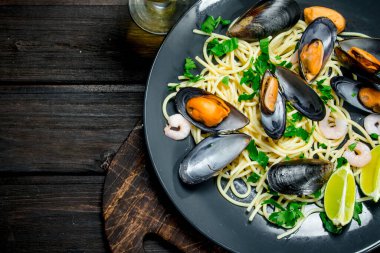 Akdeniz yemekleri. Deniz mahsulleri spagetti istiridye ve beyaz şarap. Ahşap bir arka plan üzerinde.