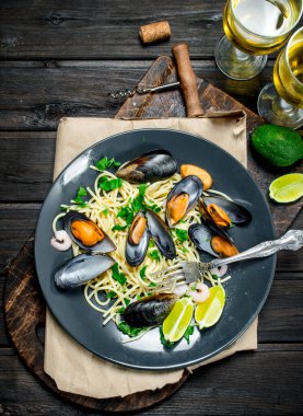 Akdeniz yemekleri. Deniz mahsulleri spagetti istiridye ve beyaz şarap. Ahşap bir arka plan üzerinde.