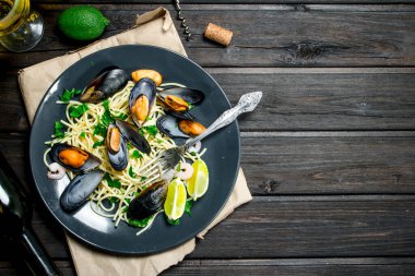 Akdeniz yemekleri. Deniz mahsulleri spagetti istiridye ve beyaz şarap. Ahşap bir arka plan üzerinde.