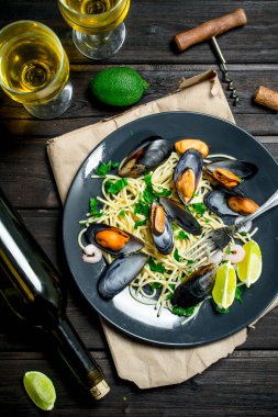 Akdeniz yemekleri. Deniz mahsulleri spagetti istiridye ve beyaz şarap. Ahşap bir arka plan üzerinde.