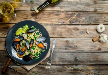 Akdeniz yemekleri. Deniz mahsulleri spagetti istiridye ve beyaz şarap. Ahşap bir arka plan üzerinde.