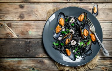 Akdeniz yemekleri. Mürekkep balığı spagetti siyah mürekkep ve istiridye. Ahşap bir arka plan üzerinde.