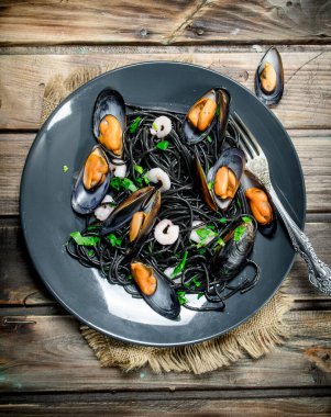 Akdeniz yemekleri. Mürekkep balığı spagetti siyah mürekkep ve istiridye. Ahşap bir arka plan üzerinde.