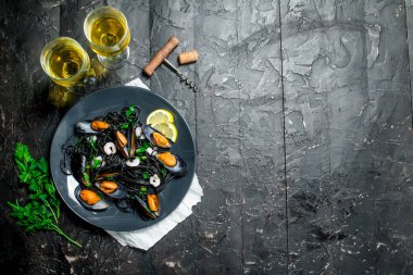 Akdeniz yemekleri. Spagetti mürekkep balığı mürekkep, istiridye ve beyaz şarap. Rustik siyah arka plan üzerine.