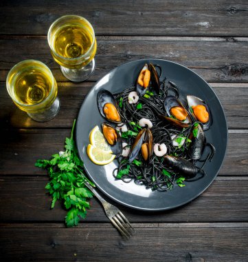 Akdeniz yemekleri. Spagetti mürekkep balığı mürekkep, istiridye ve beyaz şarap. Ahşap bir arka plan üzerinde.